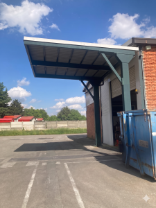 ingresso di un capannone industriale coperto con una tettoia. Tutti i tre lati sotto la tettoia sono liberi.