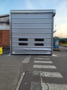 fronte di un tunnel creato davanti all'ingresso di un edificio industriale con porta rapida ad impacchettamento colore grigio