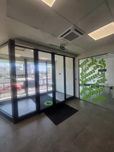 Nell'immagine si vede la bussola dell'ingresso pedonale con gestita con due porte automatiche scorrevoli con ciascuna due ante mobili e due fisse, automazione ridondante valida come uscita di sicurezza. nell'immagine tutte le ante sono in posizione di chiusura.