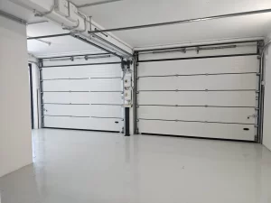 Nell'immagine si vede in primo piano una coppia di portoni sezionali chiusi, installati per la chiusura esterna.