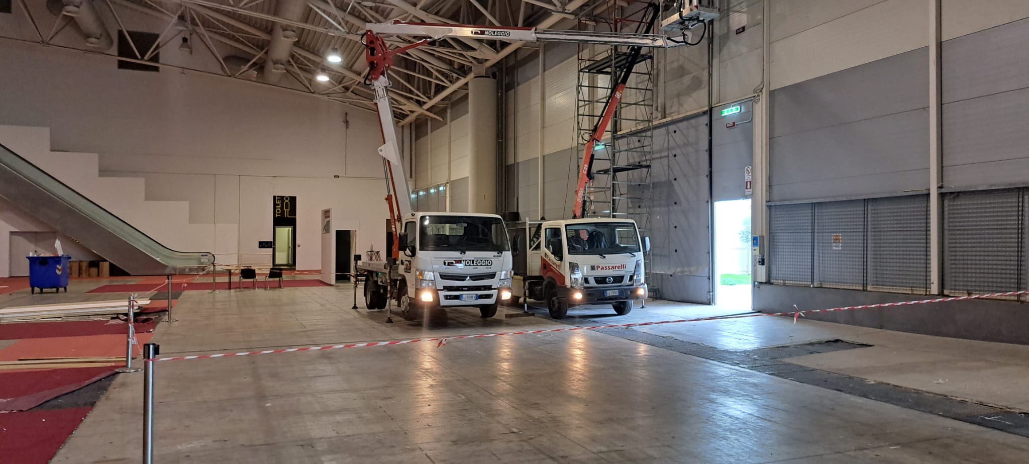 manutenzione porte sezionali in corso con utilizzo di due camion e gru