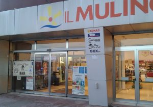 Nell'immagine si vede l'ingresso di un centro commerciale dove trovano sede diverso importanti punti vendita della GD-GDO. L'ingresso è dotato di porte automatiche a doppie ante fisse e mobili, con sistemi a sfondamento e sopraluce.