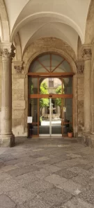 nell'immagine si vede l'ingresso della Sede Arcivescovile Siciliana. L'ingresso è dotato di una elegante porta automatica con due ante fisse e due mobili, più doppio sopraluce vetrato.