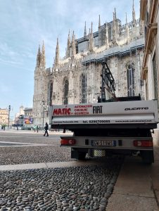 camioncino dell'azienda Matic Automazioni con i componenti delle porte scorrevoli da montare. Sullo sfondo, il duomo di Milano