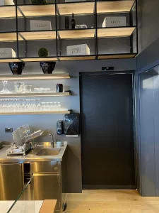 In questa foto si vede la cucina di un elegante ristorante. Una porta automatica scorrevole con un'anta realizzata con un cristallo temperato nero fumeè permette l'accesso alla sala da pranzo. 