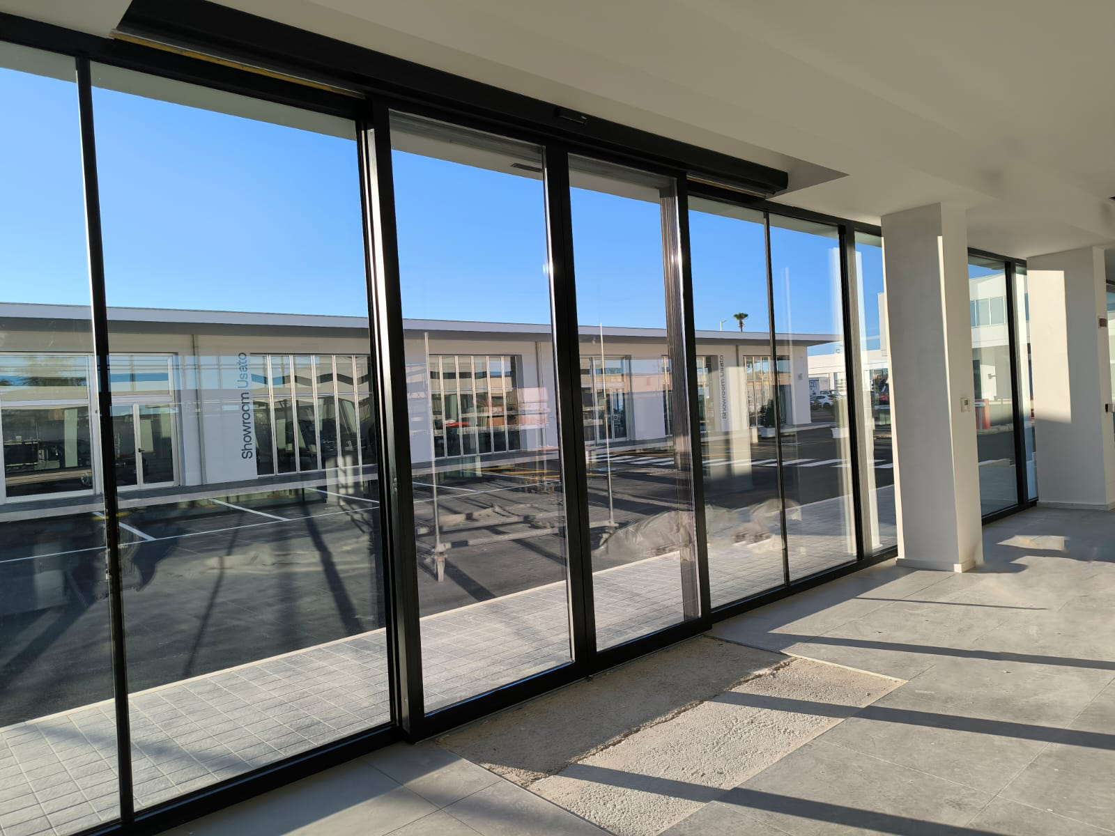 Porte automatiche scorrevoli in vetro per concessionario di auto, vista dall'interno.