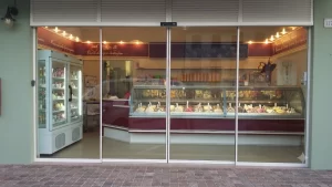 Per l'ingresso di questa gelateria è stata creata un'ampia vetrata a tutta parete con due parti fisse e due ante mobili. I serramenti scelti sono molto sottili in modo da mettere in bella vista tutto il banco pieno di gustose varietà di gelati.