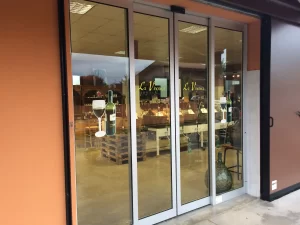 Nella foto si vede l'ingresso di una vinoteca gestito da una porta automatica scorrevole con due ante fisse e due ante mobili.