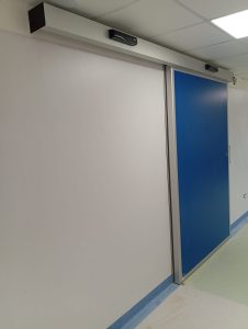 Porta scorrevole a chiusura ermetica installata all'ingresso di sala operatoria. Pannello blu cieco. Cassonetto con automazione e radar attivazione aperture e chiusure.