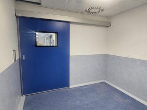 porta automatica scorrevole di colore blu e con visiva trasparente complanare che da accesso al corridoio delle sale operatorie