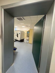 Nell'immagine si vede una porta a battente a tenuta semplice che da accesso al locale medico con gli impianti per effettuare le TAC.