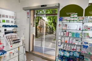 In questa immagine si vede l'ingresso di una farmacia. Per sfruttare tutto lo spazio disponibile è stata installata una porta automatica con due ante mobili scorrevoli telescopiche con impacchettamento su piccola anta fissa e parzialmente sulla parete.