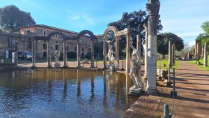 Cortile di Villa Adriana, sito storico archeologico, con una fontana, archi in pietra e statue antiche