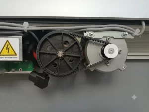 Nell'immagine si vede il cassonetto aperto. Si vede parzialmente il quadro di comando, le cinghie, la puleggia e gli organi di trasmissione nonchè i cablaggi.