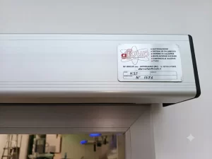 Nell'immagine si vede la parte finale del cassonetto dell'automazione, dove sono raccolti il quadro di comando e gli organi di trasmissione. Sul cassonetto si vede l'etichetta applicata dall'installatore con tutti i dati utili per riconoscere l'automazione, in caso di manutenzione.