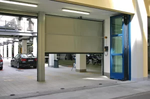Nell'immagine si vede la combinazione di porte ad avvolgimento rapido e di porte a libro finestrate per la chiusura delle aree delle concessionarie adibite alla manutenzione dei veicoli.