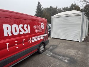 Portone sezionale di colore bianco per box auto prefabbricato e camioncino della ditta Rossi Tech che lo ha installato