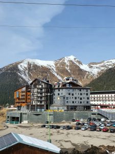 Nell'immagine si vede la grande struttura dell'hotel composta da 3 diversi corpi di edificio alti 6 piani. Sullo sfondo le montagne innevate di Foppolo, località sciistica in Lombardia.