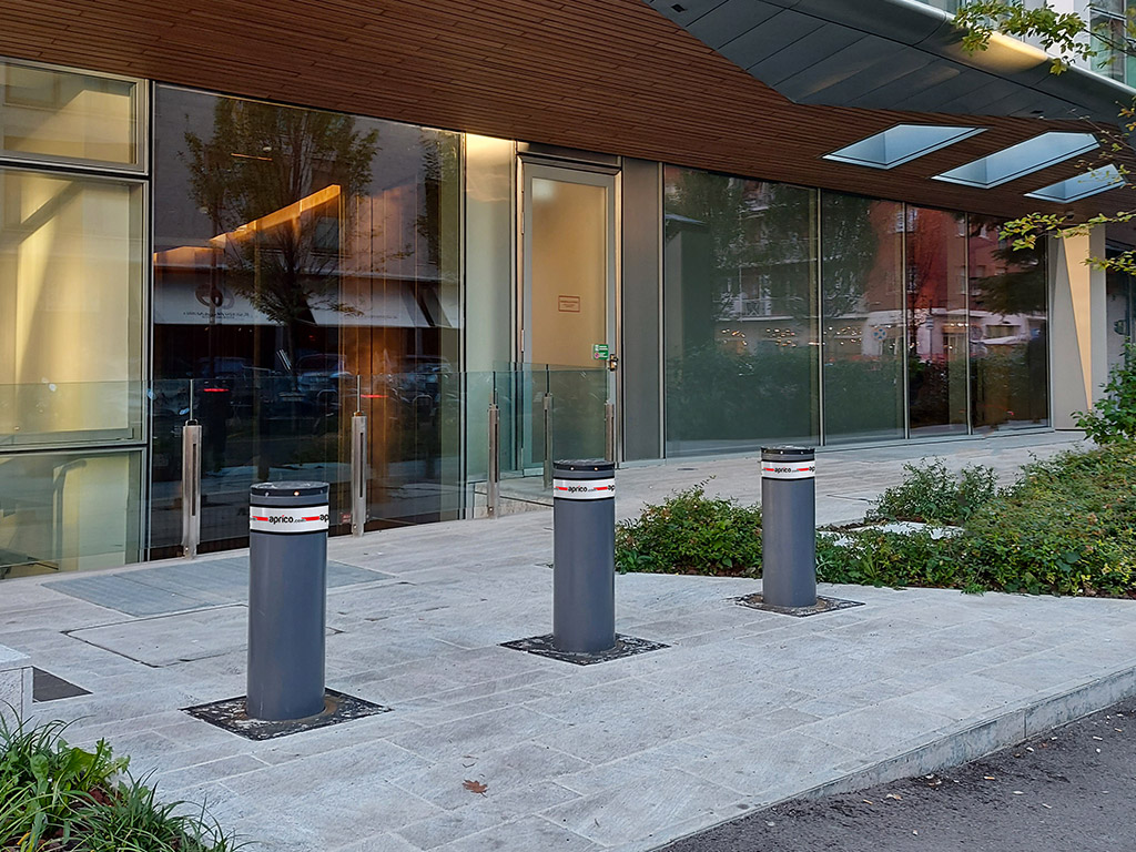L'immagine mostra l'ingresso di un edificio dove si trova una sede istituzionale di un paese estero. L'edificio è caratterizzato, a piano terra, da grande vetrate. per la protezione contro le auto-ariete sono stati installati 3 dissuasori blindati a scomparsa sulla pavimentazione di fronte alle vetrate.